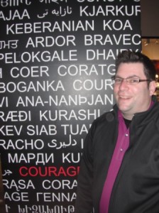 Green Ray Coaching - Environment - Shane Fortune standing in front of sign that says courage in many languages